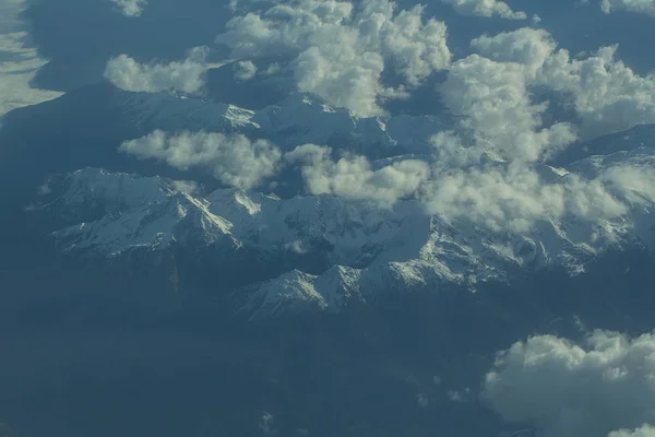 Idyllisch besneeuwde bergtoppen onder de wolken uit vliegtuig — Stockfoto