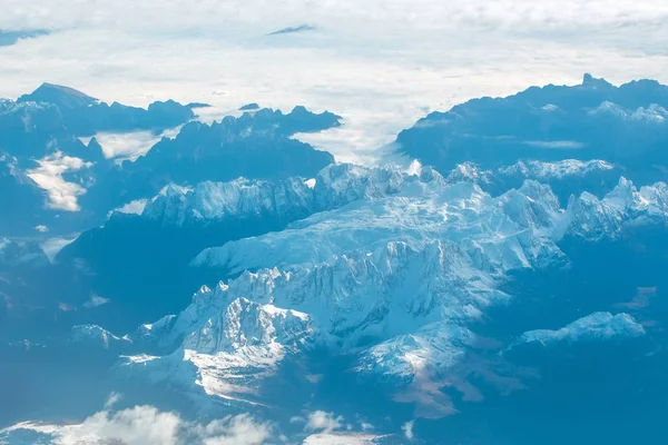 Idyllic snowy mountain peaks under clouds from plane — Stock Photo, Image
