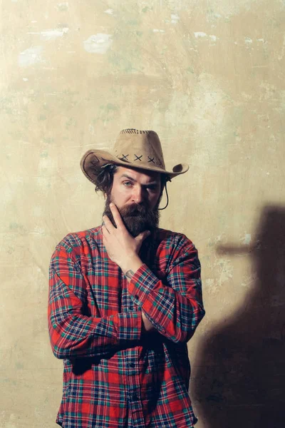 Бородатий чоловік у ковбойському капелюсі та чорна тінь на стіні — стокове фото