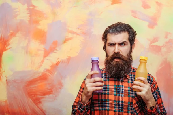Frown bearded man holding two plastic bottles — Stock Photo, Image