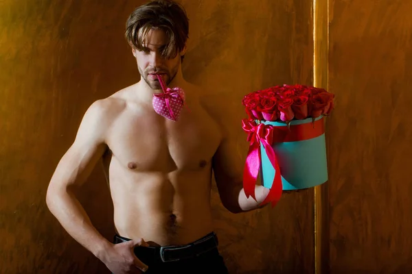 Svalnatý vousáč s sexy tělo drží červená růže box — Stock fotografie