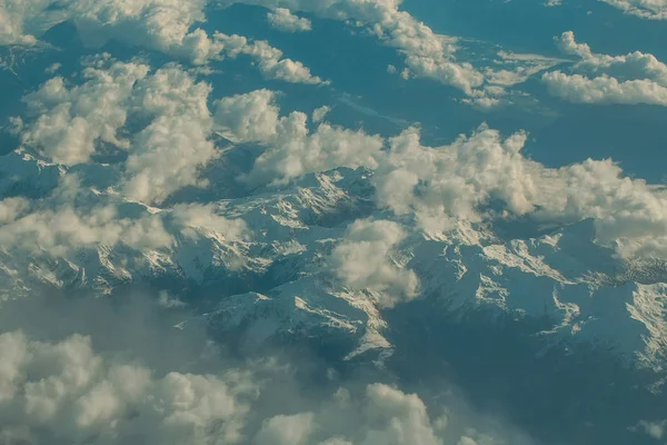 Idyllisch besneeuwde bergtoppen onder de wolken uit vliegtuig — Stockfoto