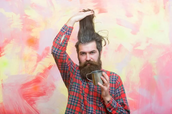 Bearded man holding stylish fringe hair and metal mug