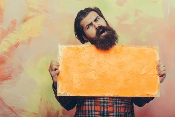 Boos bebaarde man met textuur oranje olieverf op doek — Stockfoto