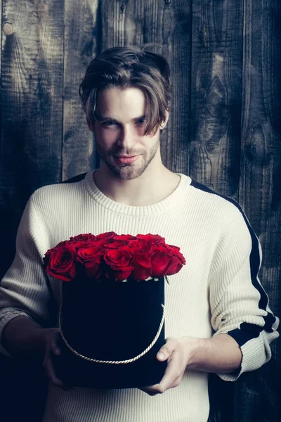 Brodaty mężczyzna szczęśliwy uśmiechający się posiada czerwone kwiaty róży w pole — Zdjęcie stockowe