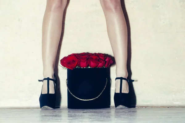 Sexy female legs with beautiful red roses in box — Stock Photo, Image