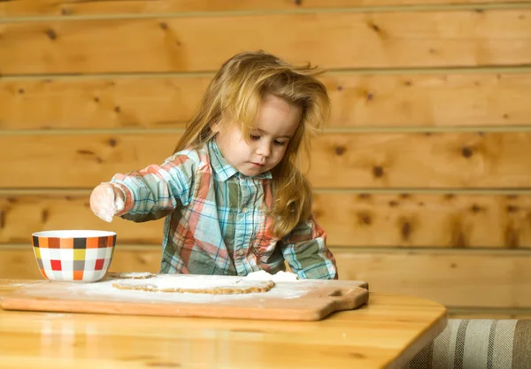 Cute child cooking with dough, flour and bowl on wood — Stock Photo, Image