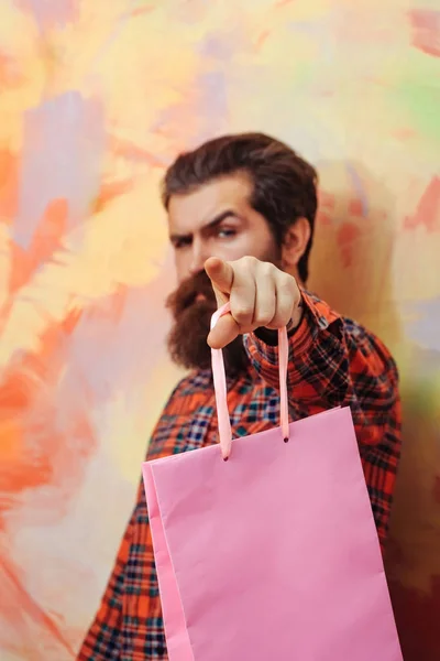 Серьёзный бородатый мужчина указывает пальцем на сумку с покупками — стоковое фото