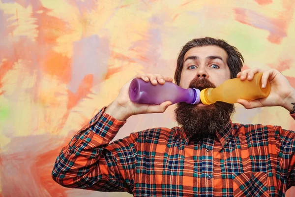 Bearded man with beard drinking from two plastic bottles — Stock Photo, Image