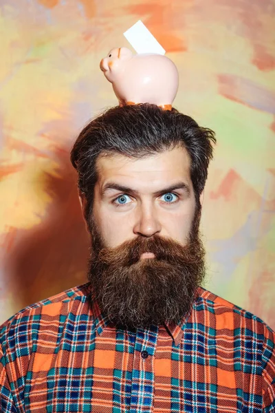 Sakallı adam kafasına pembe seramik kumbara tutan kaşlarını