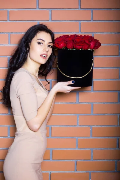 Söt flicka poserar med röda rosor i låda — Stockfoto