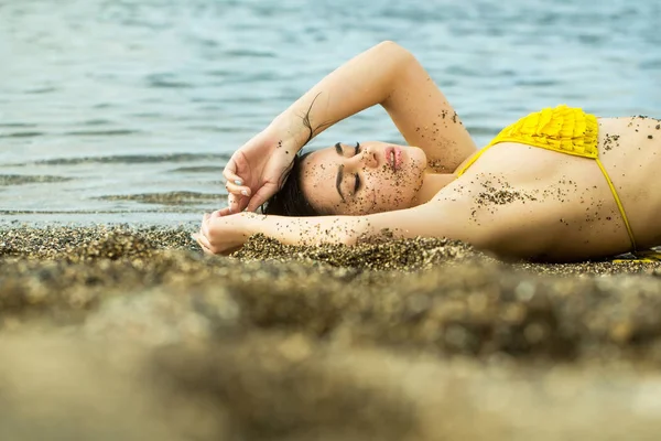 Красива дівчина в жовтому купальнику спить на морському пляжі — стокове фото