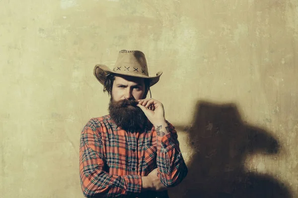 Bearded man in cowboy hat and black shadow on wall — Stock Photo, Image