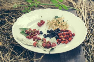 Olgun çilek plaka üzerinde yeşil yaprakları ile