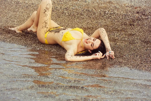 Pretty girl in yellow swimsuit lying on sea beach — Stock Photo, Image