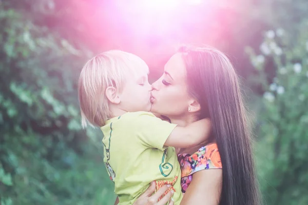 Мила маленька дитина цілує і обіймає красиву матір — стокове фото