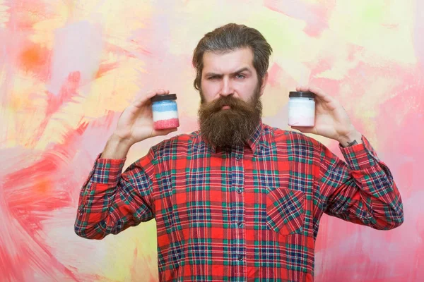 Серьезный бородатый мужчина с двумя косметическими банками — стоковое фото