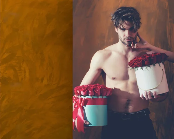 Barbudo musculoso hombre con sexy cuerpo sostiene rojo rosa caja — Foto de Stock