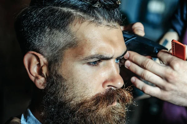 Barbudo hombre con barba conseguir corte de pelo por peluquería en la barbería —  Fotos de Stock