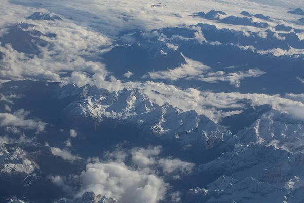 Idyllic snowy mountain peaks under clouds from plane — Stock Photo, Image