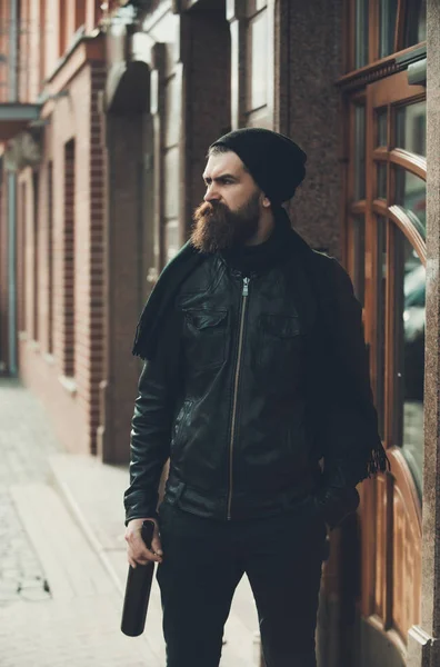 Hombre barbudo serio hipster con botella de vino en chaqueta de cuero — Foto de Stock