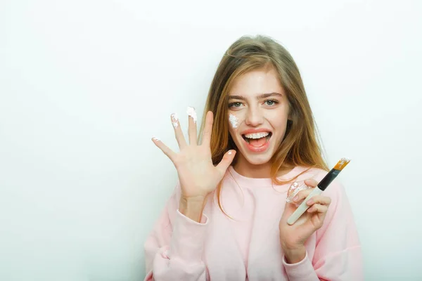 Happy pretty girl putting facial cream or mask on face — Stock Photo, Image