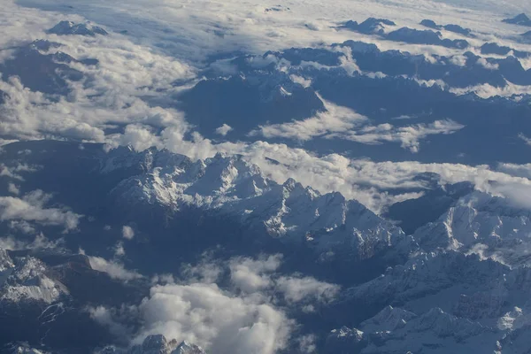 Idyllic snowy mountain peaks under clouds from plane Stock Picture