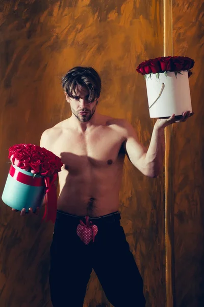 Bebaarde gespierde man met sexy lichaam houdt rood rose vak — Stockfoto