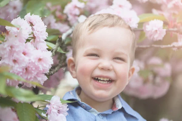 Şirin bebek çocuk arasında pembe çiçek çiçekler — Stok fotoğraf