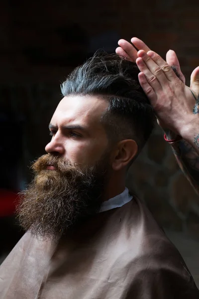 Bearded man with long beard getting hair styling