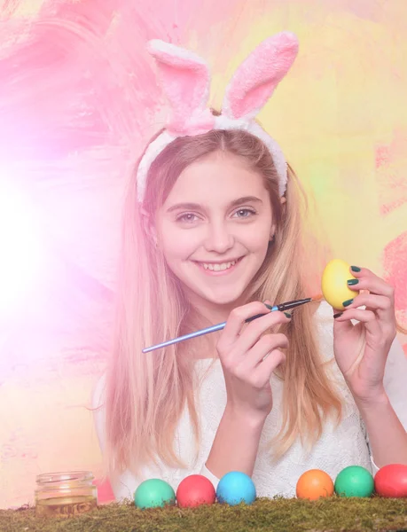 Feliz chica de Pascua en orejas de conejo con huevos y pincel — Foto de Stock