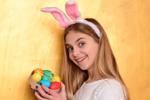 Feliz chica de Pascua en orejas de conejo con coloridos huevos pintados —  Fotos de Stock