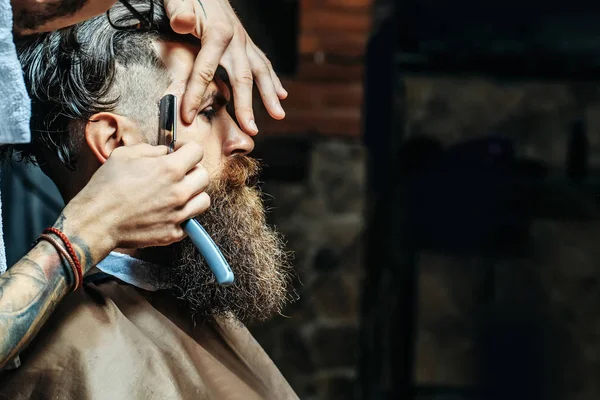 Bearded man with long beard getting hair shaving with razor — Stock Photo, Image