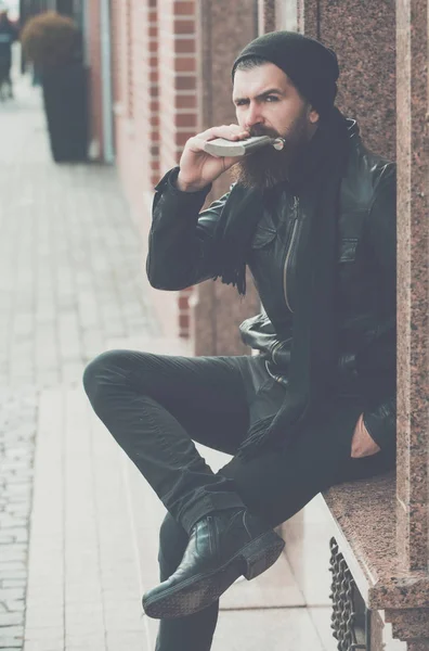 Serious bearded man hipster with wine bottle in leather jacket — Stock Photo, Image