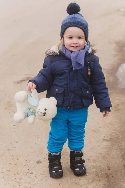 Pequeno menino feliz criança detém ursinho brinquedo inverno ao ar livre — Fotografia de Stock