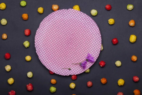 Kleurrijke smakelijke toonaangevend snoepjes en ronde roze wafer of wafel — Stockfoto