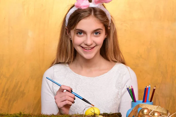 Feliz chica de Pascua en orejas de conejo con huevo, pincel, lápiz — Foto de Stock