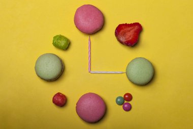 renkli macaron, badem tatlılar, çilek ve mumları saat şeklinde