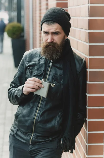 Серьезный бородатый мужчина хипстер с металлической банкой в кожаной куртке — стоковое фото