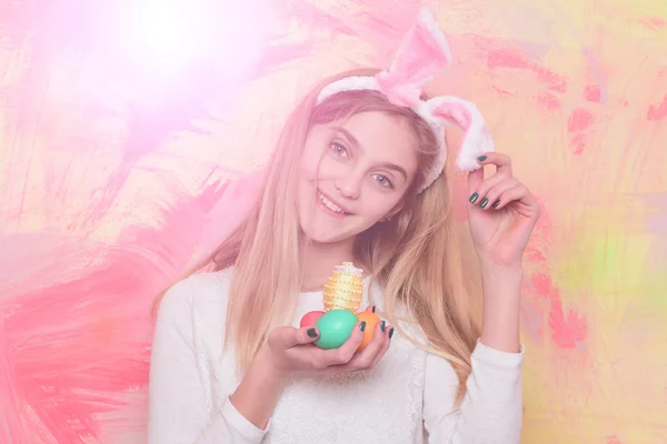 Chica feliz en orejas de conejo con coloridos huevos de Pascua pintados — Foto de Stock