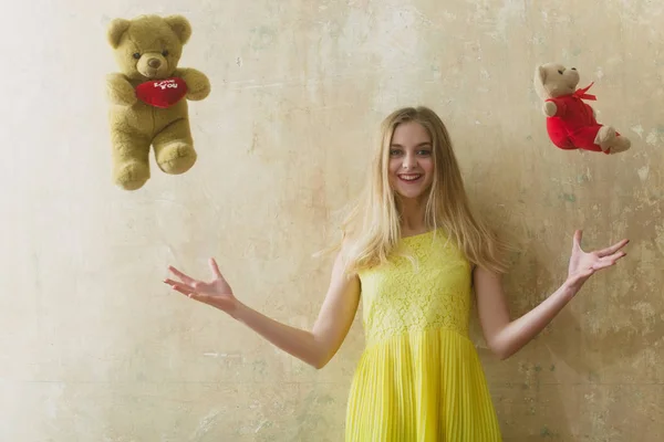 Pretty happy girl with teddy bear toy in yellow dress — Stock Photo, Image