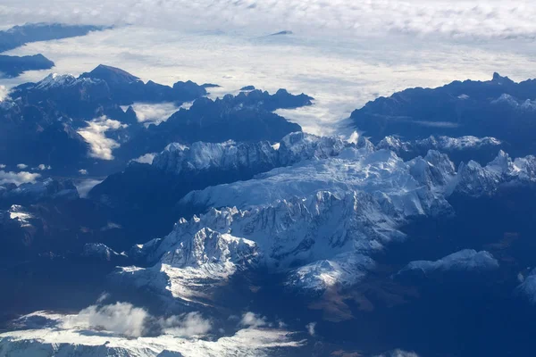 Idyllic snowy mountain peaks under clouds from plane — Stock Photo, Image