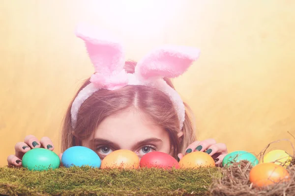 Feliz Pascua chica oculta en orejas de conejo con huevos de colores —  Fotos de Stock