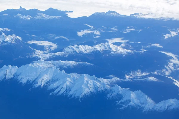 Idyllic snowy mountain peaks under clouds from plane — Stock Photo, Image