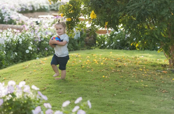 Aranyos boldog kisfiú játszik a labdát a zöld fű — Stock Fotó