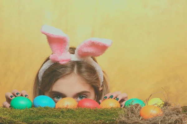 Feliz chica de Pascua en orejas de conejo con huevos de colores, musgo —  Fotos de Stock