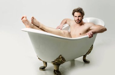 Banyoda çıplak ayakla oturan çıplak yakışıklı