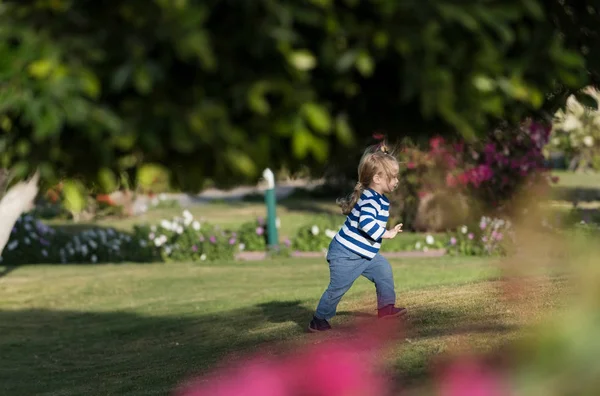 Aranyos kisfiú fut a zöld fű a kertben — Stock Fotó