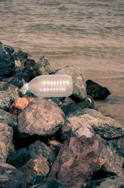 大瓶水浪费在岩石的海滩上 — 图库照片