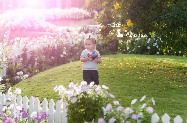 Милый мальчик играет с мячом на зеленой траве — стоковое фото